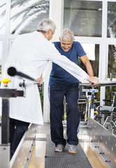 Doctor Examining Senior Man Walking In Fitness Studio