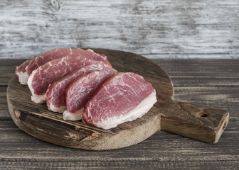 Raw sliced pork fillet on a wooden rustic board
