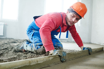 worker screeding indoor cement floor with screed 