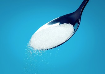 white Sugar spoon blue background.