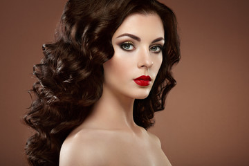 Fototapeta premium Brunette woman with curly hairstyle. Beautiful girl with long wavy hair. Perfect makeup. Fashion photo