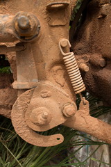 Medium close up of muddy engine component with spring on a light motorcycle in Asia