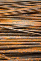 Low angle vertical MCU perspective of thin semi-rusty steel bars stacked in a horizontal position