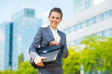 Smiling business woman in office district holding briefcase