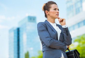 Pensive business woman with briefcase in office district