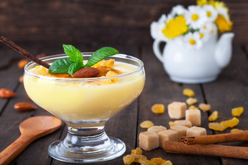 Vanilla Pudding sauce with raisins and mint on wooden background