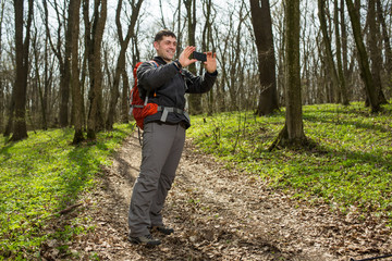 Hiking man take selfie during his walk through the forest