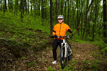 Naklejka premium Cyclist Riding the Bike on a Trail in Summer Forest