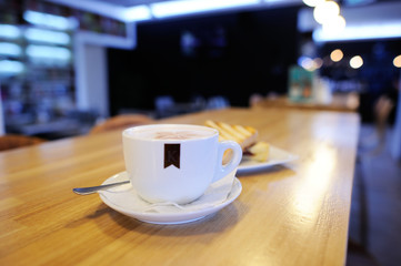 Cup of cappuccino with blur coffee shop background
