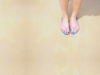 woman legs and feet stand on the sand