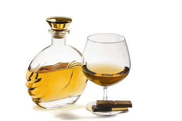 Bottle and snifter brandy with chocolate on white background