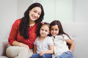 Portrait of smiling mother and daughters at home