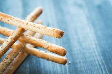 Bunch of homemade grissini breadsticks in a glass jar on wooden surface