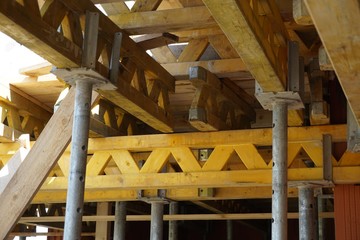 Heavy wooden beams and girders supporting construction of a concrete floor in the newly constructed building