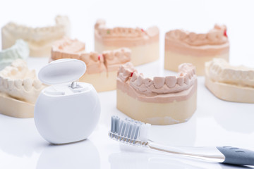 Teeth molds with dental floss and brush on a bright white table