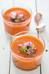 Gazpacho soup and ingredients on white wooden background
