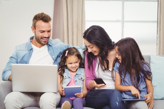 Family using modern technologies on sofa
