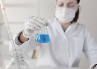 close up of woman with flask making test in lab