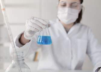 Fototapeta premium close up of woman with flask making test in lab