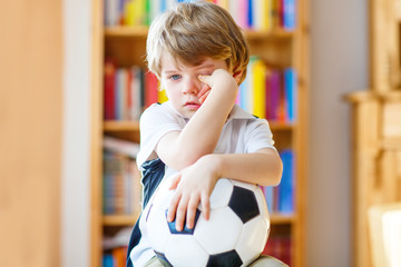 Kid boy sad about lost football or soccer game