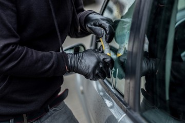 Car thief trying to break into a car with a screwdriver.