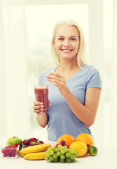 smiling woman drinking fruit shake at home