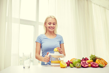 Obraz na płótnie Canvas smiling woman squeezing fruit juice at home