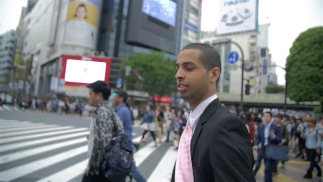 Confident young mix race Business man walking through shibuya crossing feeling successful 