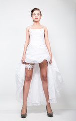 full-length bride in a wedding dress and bridal hairdo, lifted the hem of her dress. provocation playful bride