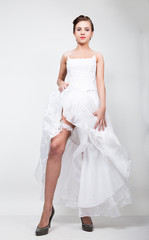 full-length bride in a wedding dress and bridal hairdo, lifted the hem of her dress. provocation playful bride