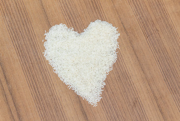 Rice laid out in a heart shape on wooden background