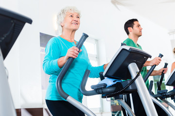 Senior woman on elliptical trainer exercising in gym