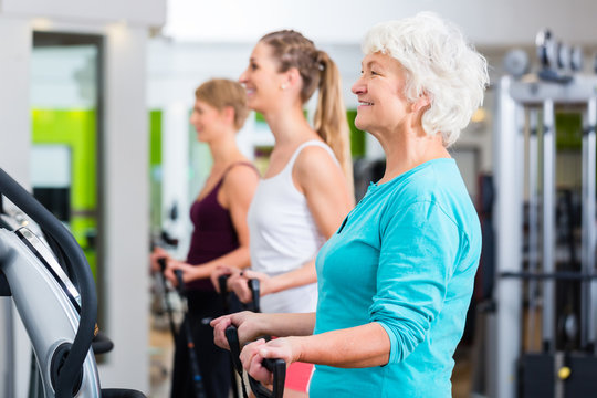 Old And Young People On Vibrating Plates In Gym