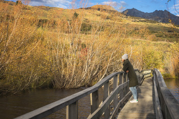 Fototapeta na wymiar woman walks along boardwalk/path traverses wetlands