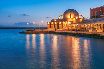 Fototapeta premium Picturesque view of Venetian quay of Chania with Kucuk Hasan Pasha Mosque during mornng blue hour before sunrise, Crete, Greece