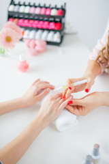 Obraz na płótnie Canvas Woman in salon receiving manicure by nail beautician
