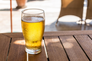 Glass of light beer on the wooden table.