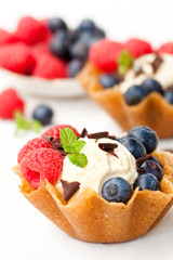 brandy  snaps baskets with soft cream cheese and berries on whit