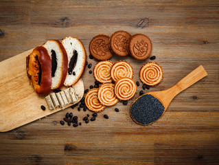 There are Pieces of  Roll with Poppyseed,Cookies,Halavah,Chocolate Peas,Tasty Sweet Food on the Wooden Background,Top View