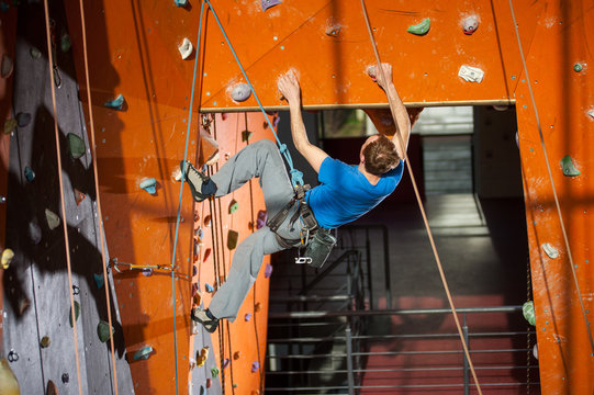 Athletic climber climbs on an indoor rock-climbing wall with special equipment