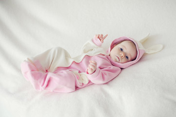 Fototapeta na wymiar Baby lying on white blanket in Bunny costume.