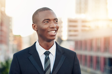 Fototapeta premium Young African businessman smiling while looking away optimistical