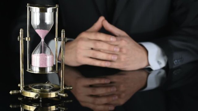 hourglass. time is running out. a man in a business suit