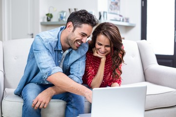 Obraz na płótnie Canvas Smiling couple using laptop 
