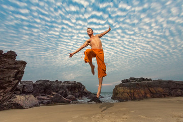 Young man high jumping on beach