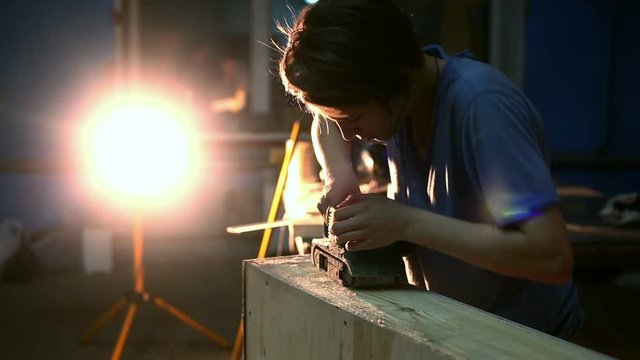 Carpenter polishing wood using electric grinder with polishing extender. close up