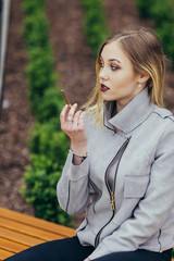 Young woman smoking cigarette on the bench