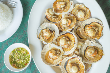 Baked scallops with butter and soy sauce in natural scallop shell delicious Thai sea food.