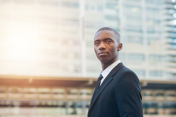 Young African businessman looking serious in a city with sunflare
