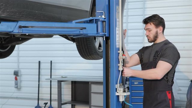 Mechanic lifts car by hydraulic lift
